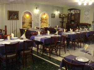Szent György Fogadó في بيتْش: غرفة طعام مع طاولات وكراسي مع مفارش أسرّة زرقاء