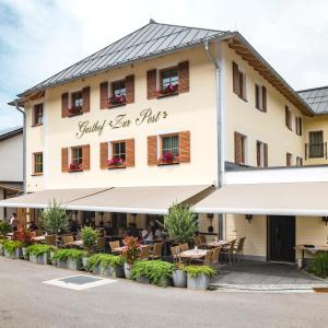 ein Hotel mit Tischen und Stühlen davor in der Unterkunft Gasthof - Hotel Zur Post in Neukirchen am Teisenberg