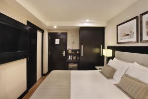 a bedroom with a large white bed with a black headboard at Miramar By Windsor Copacabana in Rio de Janeiro