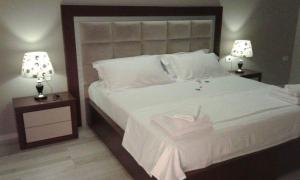 a bedroom with a large white bed with two lamps at Hotel Magllara in Sarandë