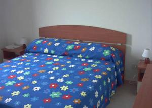 Una cama con un edredón azul con flores. en Villetta Dolce, en Campofelice di Roccella