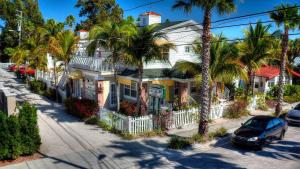 een wit huis met palmbomen voor een straat bij Coconut Inn Pass-a-Grille Beach in St Pete Beach