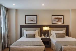 a bedroom with two beds and a table with a lamp at Miramar By Windsor Copacabana in Rio de Janeiro