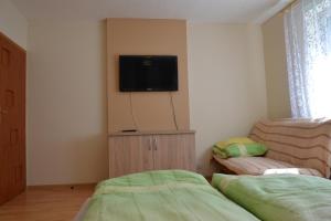 Pokoje Gościnne Bartek في ياستراوبيا جورا: غرفة نوم مع أريكة وتلفزيون على الحائط