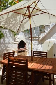 einen Holztisch mit einem Regenschirm und einem Pizzaofen in der Unterkunft Trulli Casa Alberobello in Alberobello