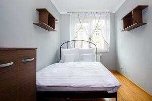 Schlafzimmer mit einem Bett mit weißer Bettwäsche und einem Fenster in der Unterkunft Supreme Apartments Ściegiennego in Stettin