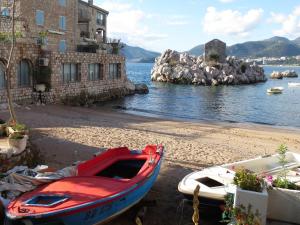 un barco sentado en una playa al lado de un edificio en Apartment Irena, en Sveti Stefan