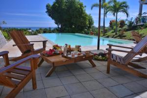 un patio avec deux chaises et une table à côté d'une piscine dans l'établissement Hotel Mahita Tsara, à Djamandjary