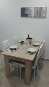 una mesa de madera con sillas, platos y copas de vino en Apartment Smodlaka, en Dugopolje