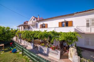 a large white building with a lot of vines at Apartments Antonio in Rab