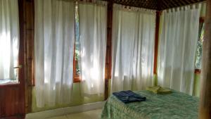 1 dormitorio con cortinas blancas, 1 cama y ventana en Plan De Guinea, en Chalzentla