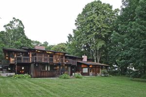 a large wooden house with a lawn in front of it at The Cottage in Stockbridge