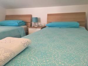 two beds in a hotel room with blue pillows at Suite sul mare in Mascali