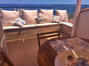 a bench on a balcony with pillows and a table at Suite sul mare in Mascali