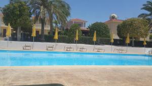 a swimming pool with chairs and umbrellas in front of a building at Villa Galleria in Perivolia