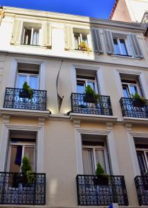 un edificio con balcones y macetas. en Hotel l'Hotera en Cannes