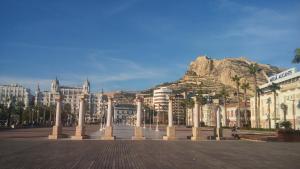 una calle con columnas y edificios con una montaña en el fondo en LOVE ALICANTE, en Alicante