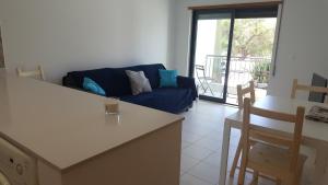 uma sala de estar com um sofá azul e uma mesa em Vista das Ondas Apartment em Albufeira