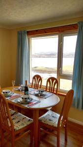a dining room table and chairs with a table and a window at 7 Habost in Balallan