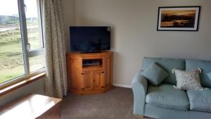 a living room with a blue couch and a television at 7 Habost in Balallan