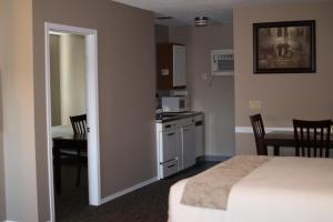 a bedroom with a bed and a kitchen and a table at Red Coat Inn Motel in Fort Macleod