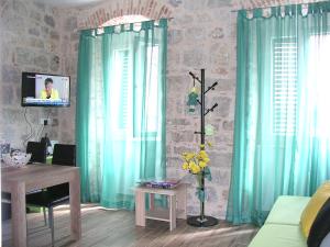een woonkamer met blauwe gordijnen, een tafel en een televisie bij Apartmani KLARA i GRACIA in Split