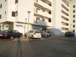 um parque de estacionamento com carros estacionados em frente a um edifício em apartamento em albufeira em Albufeira