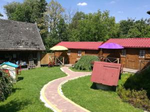 a garden with two buildings with umbrellas and a path at Gościniec Grek Zorba - pokoje i domki 4 osobowe - 16km od Zator Energylandia in Inwałd