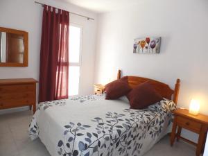 un dormitorio con una cama y una ventana en Apartamentos Medano - Mirazul 2, en El Médano