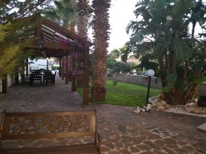 a patio with a bench and a table and palm trees at Villa Galleria in Perivolia
