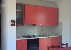 a red kitchen with a sink and red cabinets at Villetta Dolce in Campofelice di Roccella