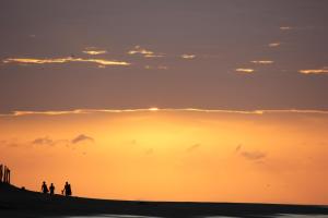 a group of people standing on a beach at sunset at Casa en el Aire in Los Órganos