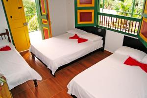 Habitación con 2 camas y almohadas rojas. en Hostal Casa de Los Taitas, en Salento