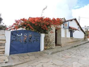 a blue gate on a house with red flowers at Pousada Casa da Serra in São Thomé das Letras