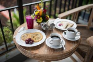 stół z dwoma filiżankami kawy i talerzami jedzenia w obiekcie Pecatu Ubud Guest House w mieście Ubud