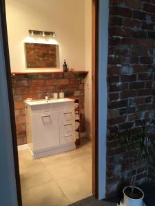 a bathroom with a sink and a brick wall at Private, comfortable studio. in Wellington