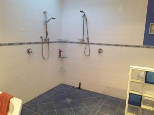 baño con 2 duchas y suelo de baldosa. en Beach B&B, en Waihi Beach