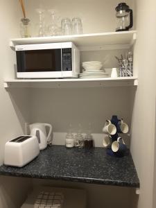 a kitchen counter with a microwave on a shelf at Beach B&B in Waihi Beach