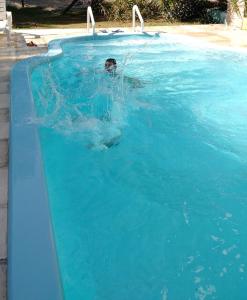 a person is swimming in a swimming pool at Cabañas Ensueño del Lago in Termas de Río Hondo