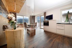 a kitchen with white cabinets and a dining room with a table at Hotel Christine in Gargazzone