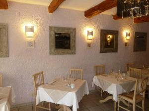 Sainte-Cécile-les-VignesにあるLogis Hôtel Restaurant La Farigouleのダイニングルーム(白いテーブルクロス付きテーブル2台付)