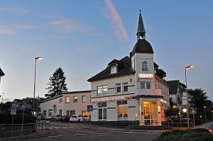 ein weißes Gebäude mit einem Kirchturm auf einer Straße in der Unterkunft Hotel Stadt Reinfeld in Reinfeld