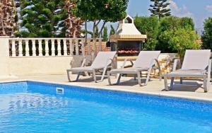 een zwembad met 2 ligstoelen en een open haard bij Acropolis Sea View Villa in Polis Chrysochous