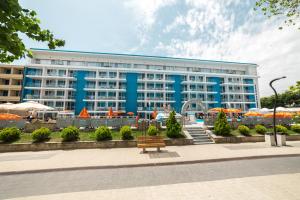 un gran edificio azul con un banco delante en Hotel Bavaria Blu, en Mamaia