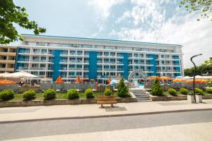 un grand bâtiment bleu avec un banc devant lui dans l'établissement Hotel Bavaria Blu, à Mamaia