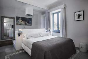 a white bedroom with a large bed and a window at La Suite Boutique Hotel in Procida