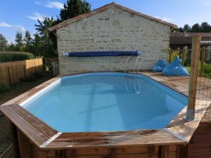 a swimming pool with a wooden deck and a brick building at La Balangere in Coulon