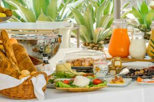 a table with a breakfast of bread and cheese and juice at Cave Bianche Hotel in Favignana