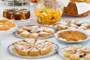 a table with many different types of pastries and pies at Cave Bianche Hotel in Favignana