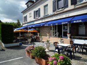 un restaurant avec des tables et des chaises en face d'un bâtiment dans l'établissement Le Relais de la route bleue, à Saint-Loup